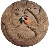Rundes Holzschnitzbild, das zwei Hände zeigt, die nach Früchten an einem Ast greifen.