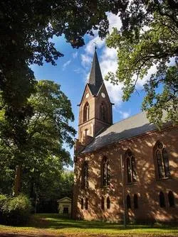 St. Michael Kirche in Werneuchen, Deutschland, umrahmt von grünen Bäumen und blauem Himmel.