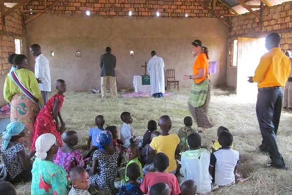 Gruppe von Erwachsenen und Kindern versammelt in einer einfachen, ländlichen 