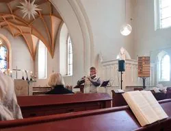 Flötist spielt Musik in einer Kirche mit Kirchenbänken und Altar.