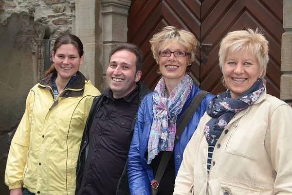 Vier lächelnde Erwachsene posieren im Freien vor einem Gebäude.