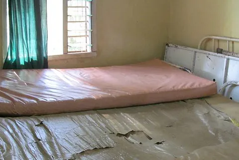 Karges Zimmer mit einer Matratze auf dem Boden und einem Fenster.