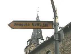 Rundes Holzschnitzbild, das zwei Hände zeigt, die nach Früchten an einem Ast greifen.