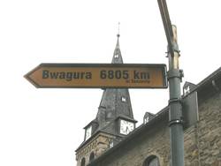 Rundes Holzschnitzbild, das zwei Hände zeigt, die nach Früchten an einem Ast greifen.